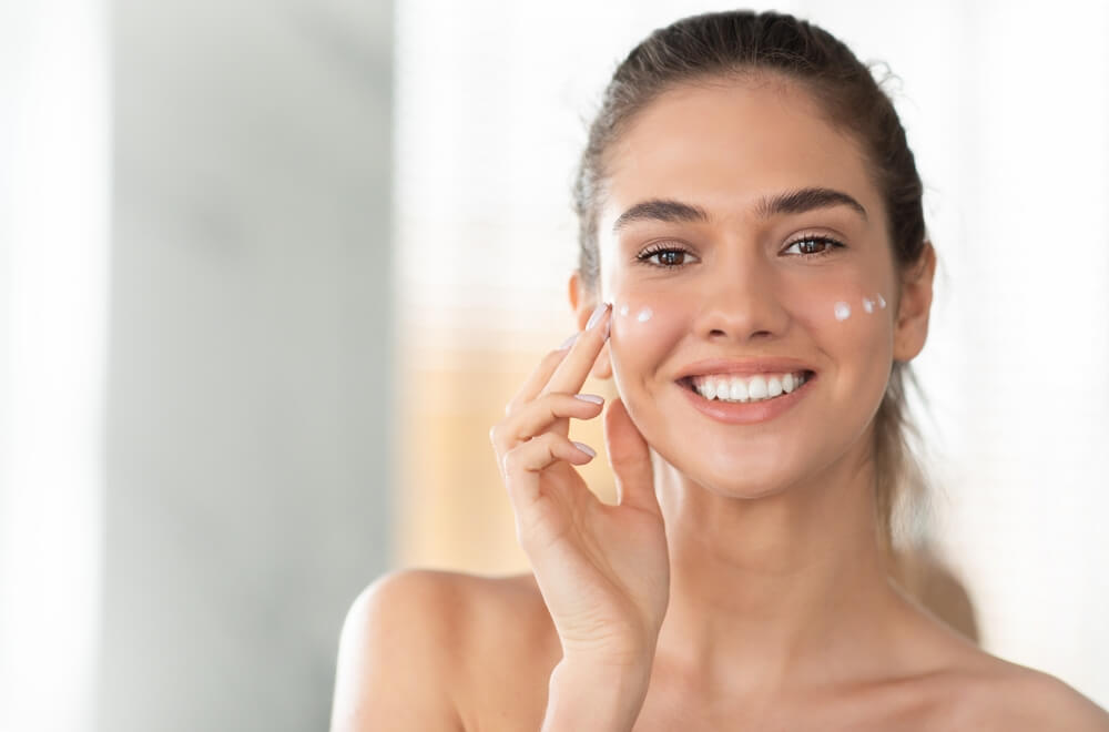 Woman applying moisturizing cream to skin