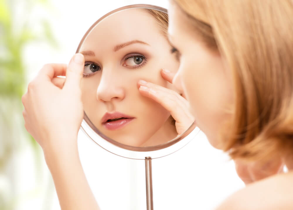 Woman looking at skin in mirror