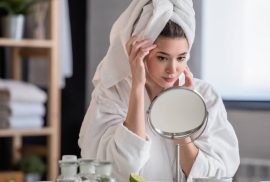 Woman looking at skin in mirror