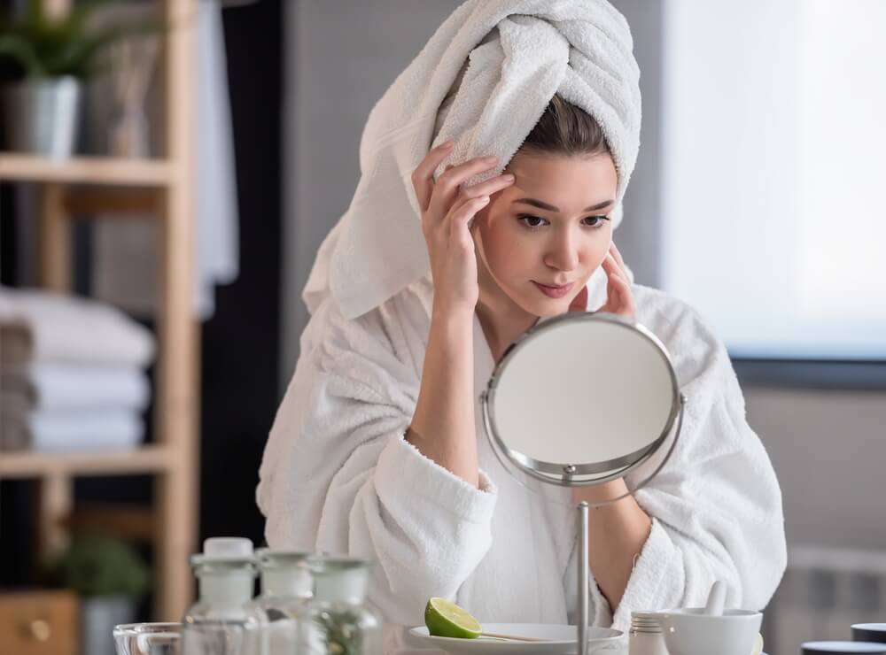 Woman looking at skin in mirror