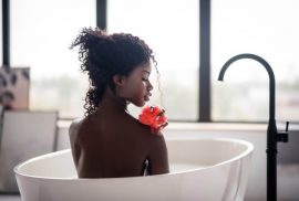 Woman in bath using loofah