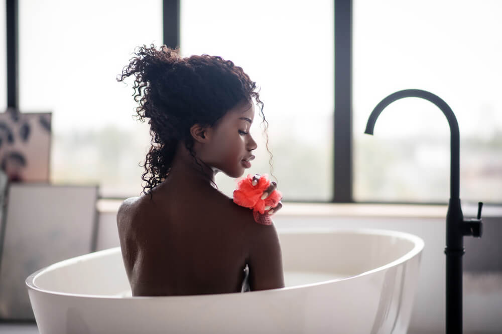 Woman in bath using loofah