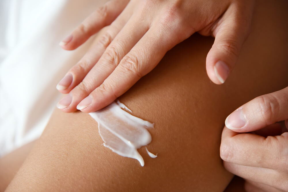 Woman applying body lotion