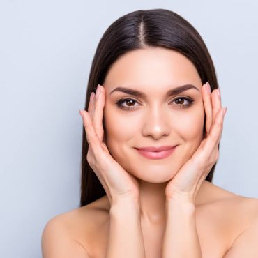 woman smiling holding face