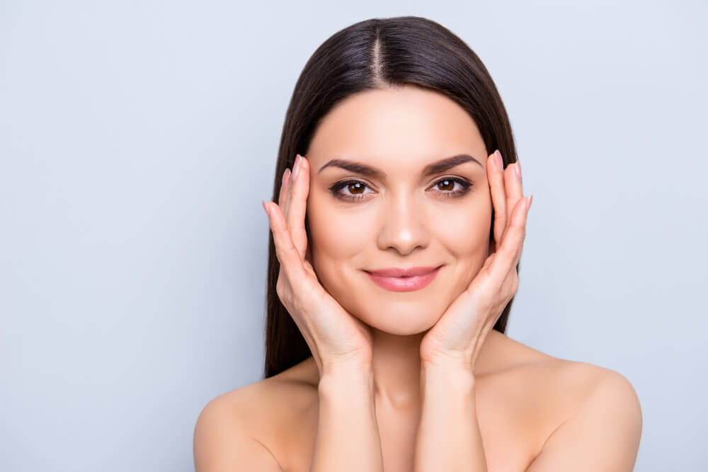 woman smiling holding face