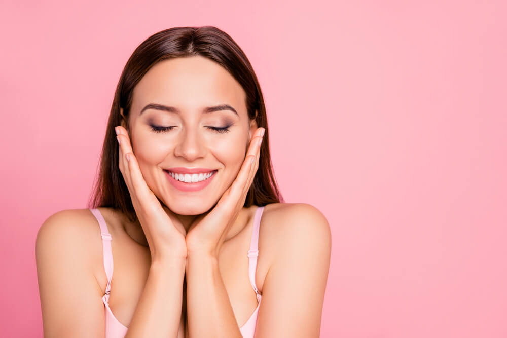 smiling woman with hands on face